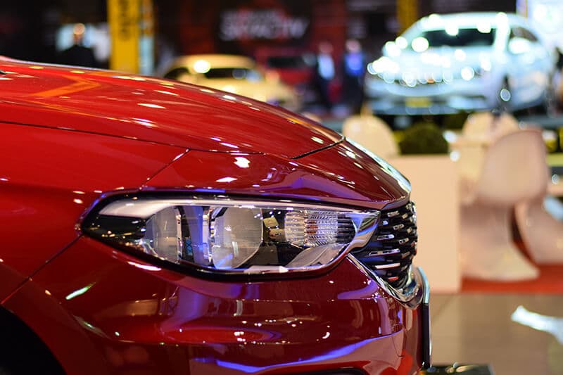 Red car front with sleek headlights displayed in a showroom