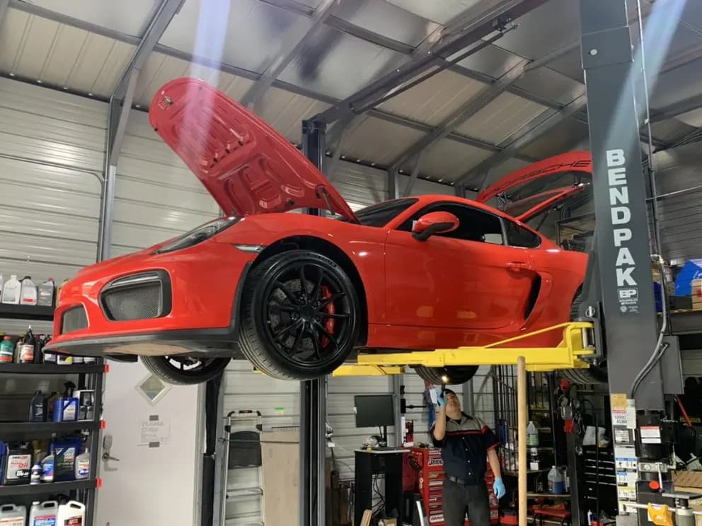 Red sports car on BendPak lift with hood raised for inspection